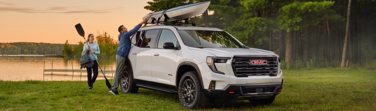 A family putting a kayak on top of a GMC at a lake